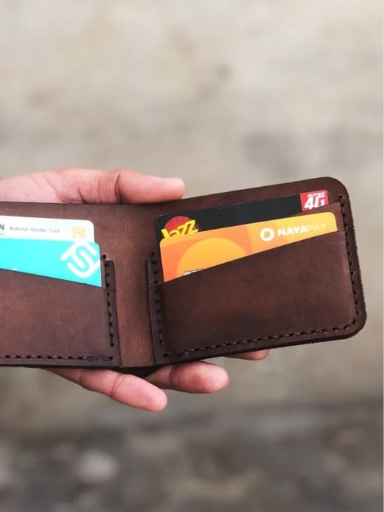 The Drifter Travel Wallet open, holding an ID card and cash