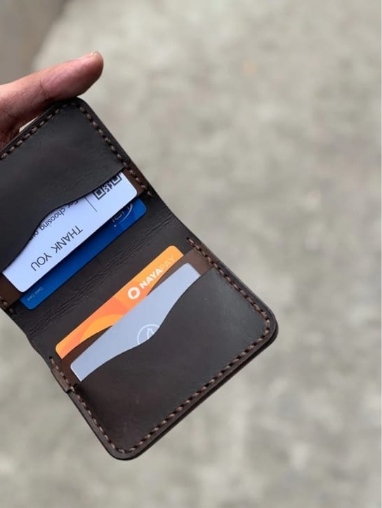 The Rancher Bifold Wallet open, holding cards and cash